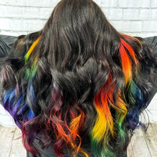 add a pop of color with rainbow highlights on your long brunette hair